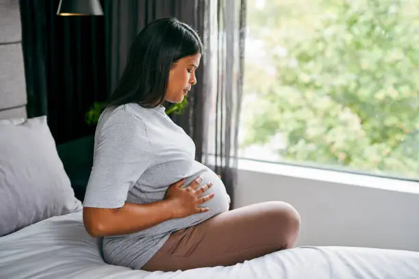 pregnant woman sitting on a bed