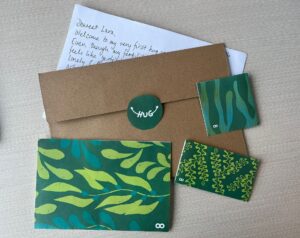 Hoopsy Fertility Snail Mail envelop laid out on a table, featuring a letter, affirmation and mindfulness cards, and a recipe to help you on your TTC journey.