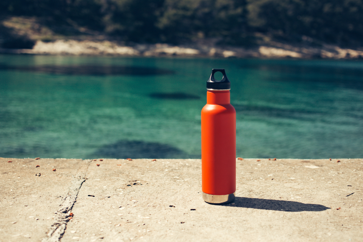 metal water bottle by the water